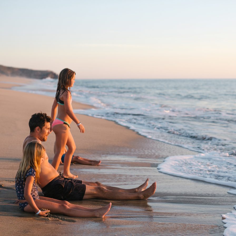 Padre seduto di fronte al mare con i suoi 2 figli. In vacanza. Turismo slow