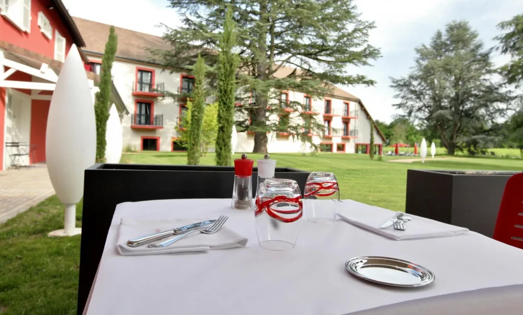 Image qui montre une table du restaurant Rouge & Blanc, à l'intérieur de Les Maritonnes parc & vignoble restaurant, avec la maison en fond