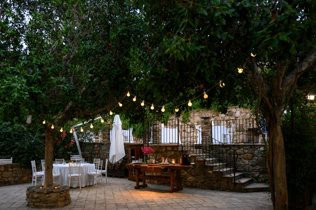 Le jardin de Dattilo, relais & ristorante adresse Teritoria en Calabre, Italie. Arbres avec lumières chaleureuses et tables avec nappe blanche. Country chic